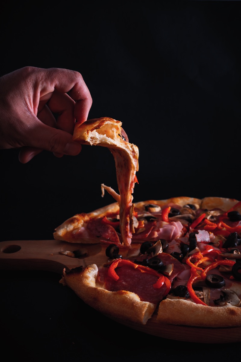 Ruka bere kus pizzy s taženým sýrem